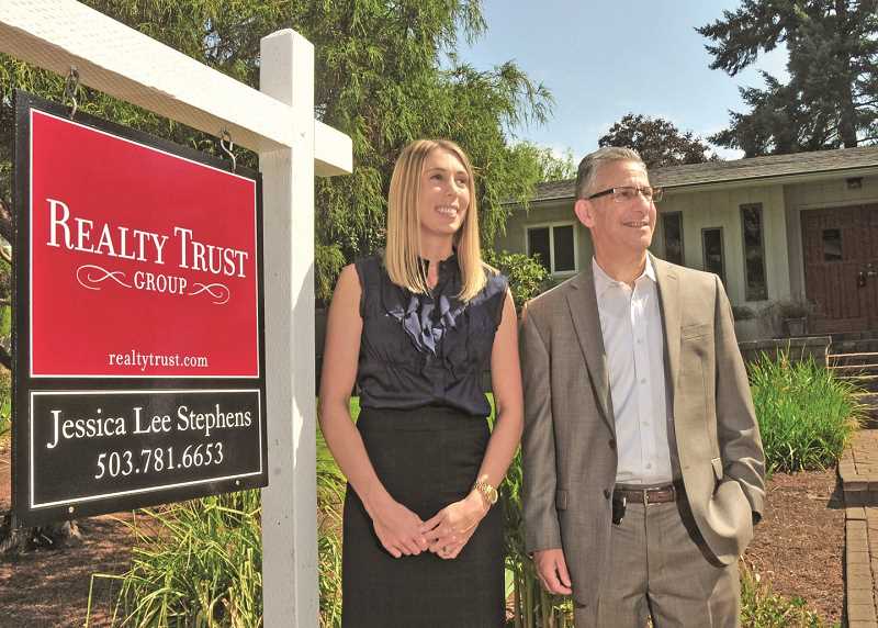 REVIEW PHOTO: VERN UYETAKE - Joe Menashe, managing principal broker for Realty Trust Group, and listing agent Jessica Lee Stephens pose outside a home for sale on Rainbow Drive in Lake Oswego. Menashe says the basic laws of supply and demand are driving the local market.